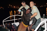 Dos guardias civiles sujetan a uno de los inmigrantes, sin fuerzas para mantenerse en pie. 