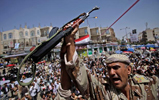Un oficial yemen empua su AK-47, al tiempo que arenga a los manifestantes antigubernamentales en Sanaa