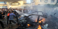 Varios hombres intentan apagar el fuego al vehculo de Ahmen Yabari tras el antentado.