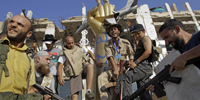 Rebeldes libios posan con la famosa estatua del puo de oro.