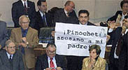 El diputado Fidel Espinoza muestra una pancarta contra Pinochet